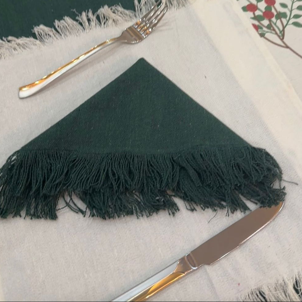 Green placemats with fringe on a tablecloth with floral patterns