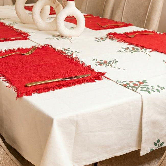 Dining table set with red placemats, white tablecloth, and decorative vases.