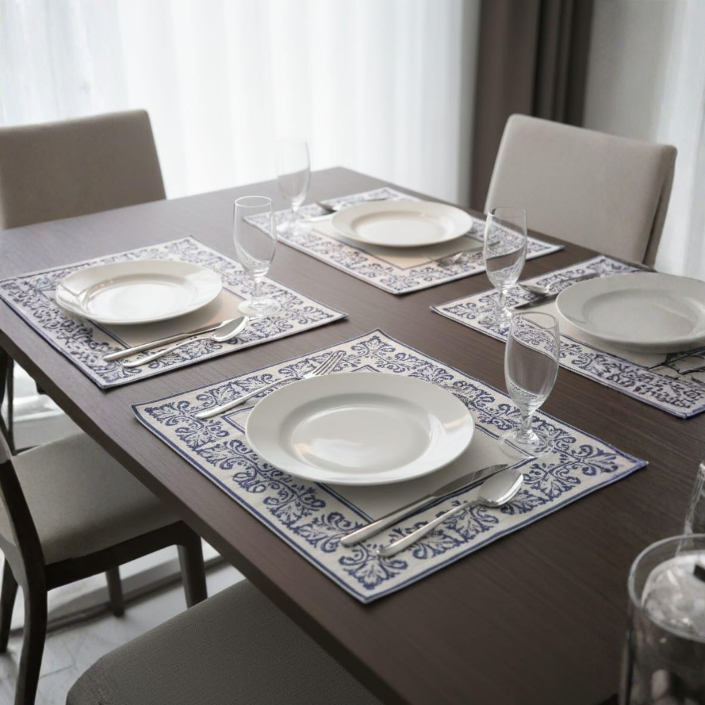Dining table set with plates, glasses, and cutlery on decorative placemats.