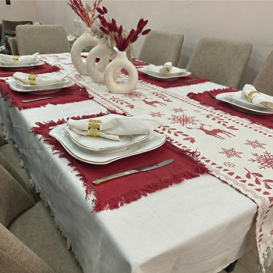 Dining table set with a red and white patterned tablecloth, red placemats, and gold cutlery.