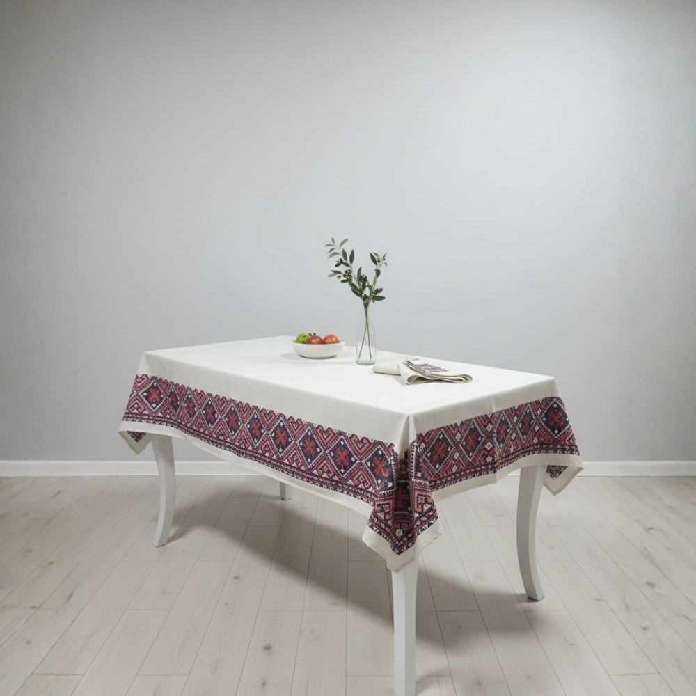 Table with a decorative tablecloth featuring a red and blue pattern on a white wall background.