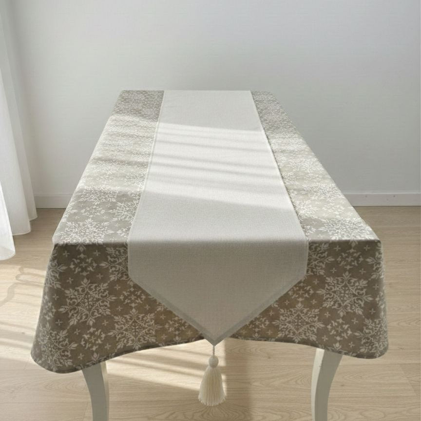 Table with a decorative tablecloth and runner on a wooden floor.