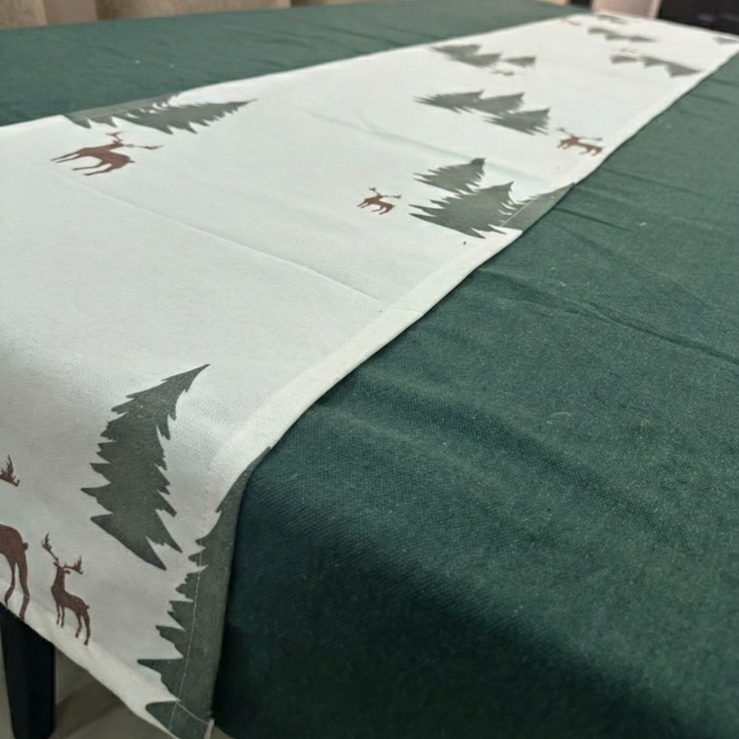Table runner with deer and tree pattern on a green tablecloth