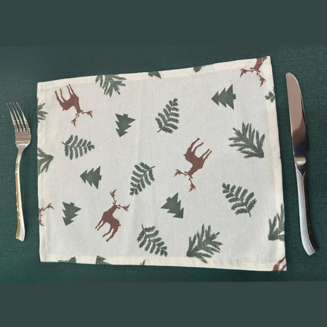 Placemat with deer and tree pattern on a green surface with cutlery.